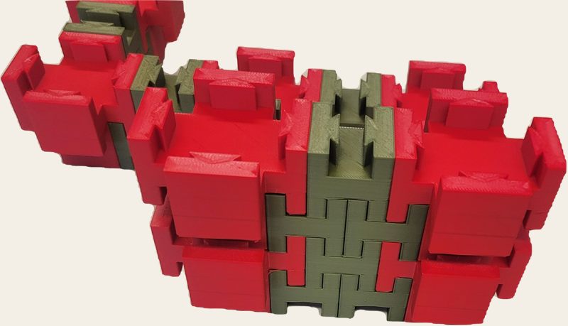 Red and green 3D printed interlocking toy blocks locked into walls